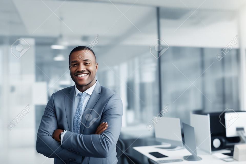 Uśmiechnięty Afroamerykański biznesmen stojący samotnie w dużym biurze