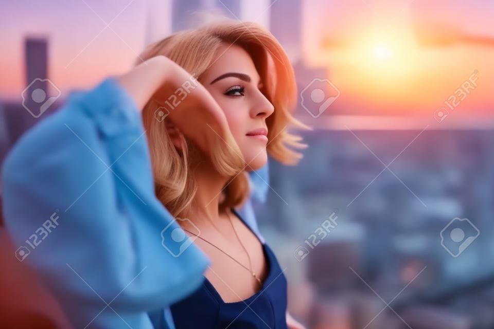 Stijlvolle vrouw geniet van een ongelooflijk uitzicht over de stad vanaf het dak bij zonsondergang vrijheid concept levensstijl