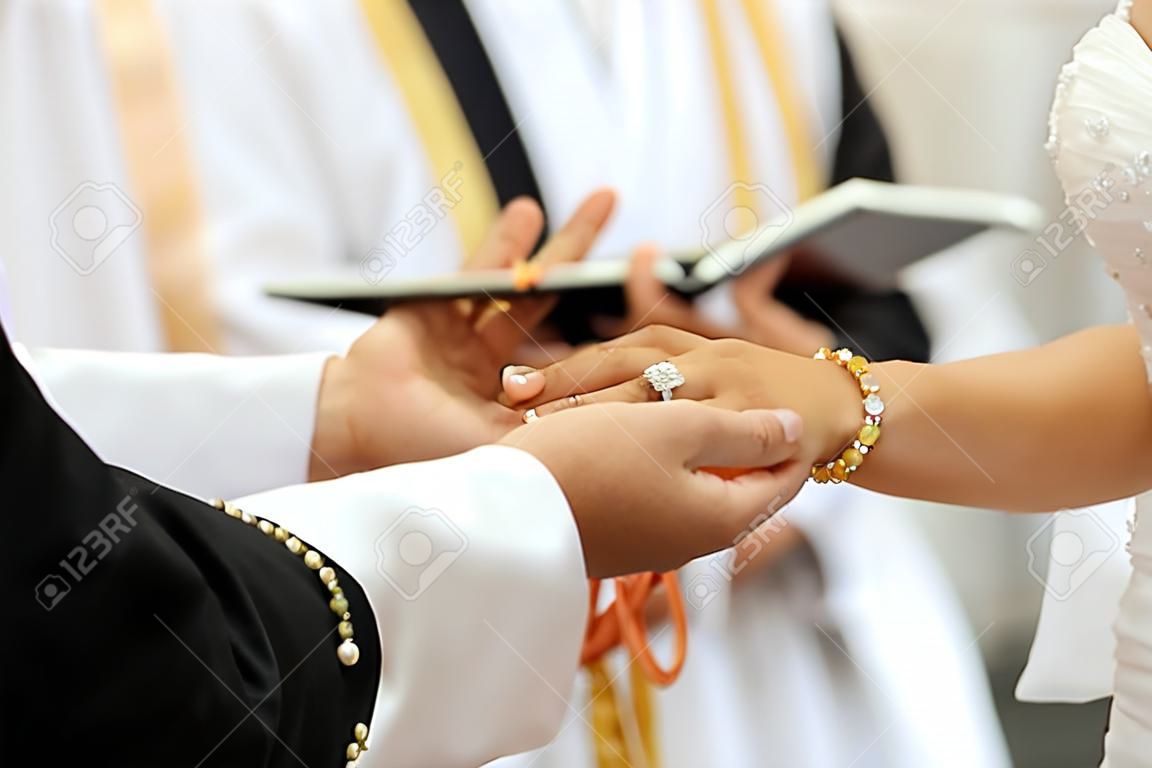 Braut, die einen Ring auf den Finger des Bräutigams während der Hochzeitszeremonie setzt