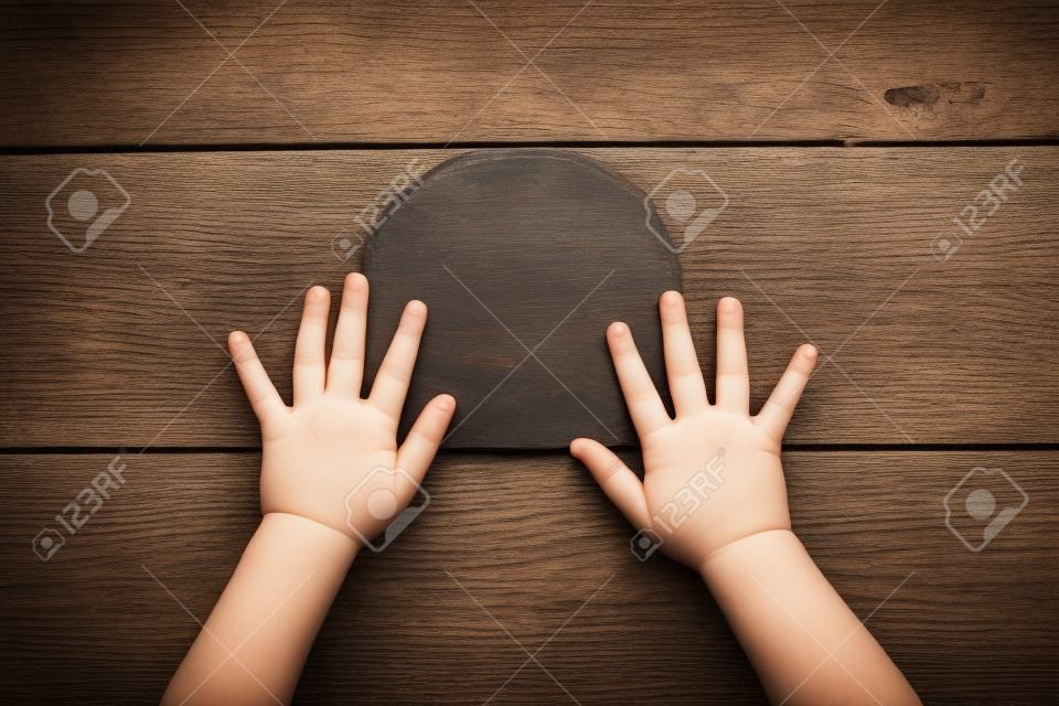 Children's hands is located on an old wooden plate