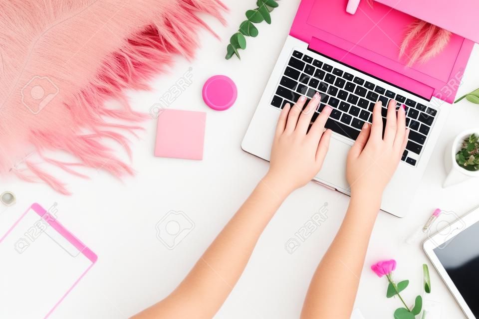 Flat lay home office desk. Female workspace with laptop, eucalyptus branch, accessories on pink background. Top view feminine background. Lifestyle blog hero.