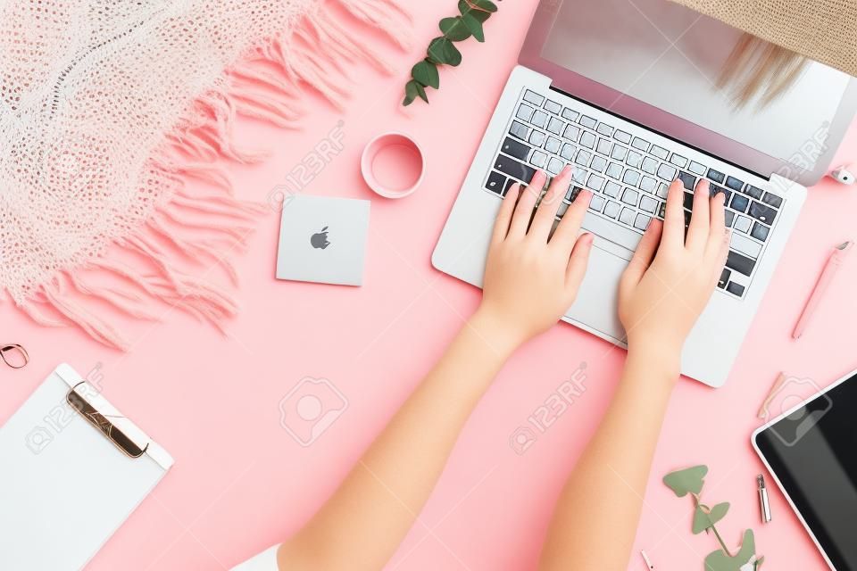 Flat office laici. Area di lavoro femminile con computer portatile, ramo di eucalipto, accessori su sfondo rosa. Vista dall'alto sullo sfondo femminile. Lifestyle blog eroe.