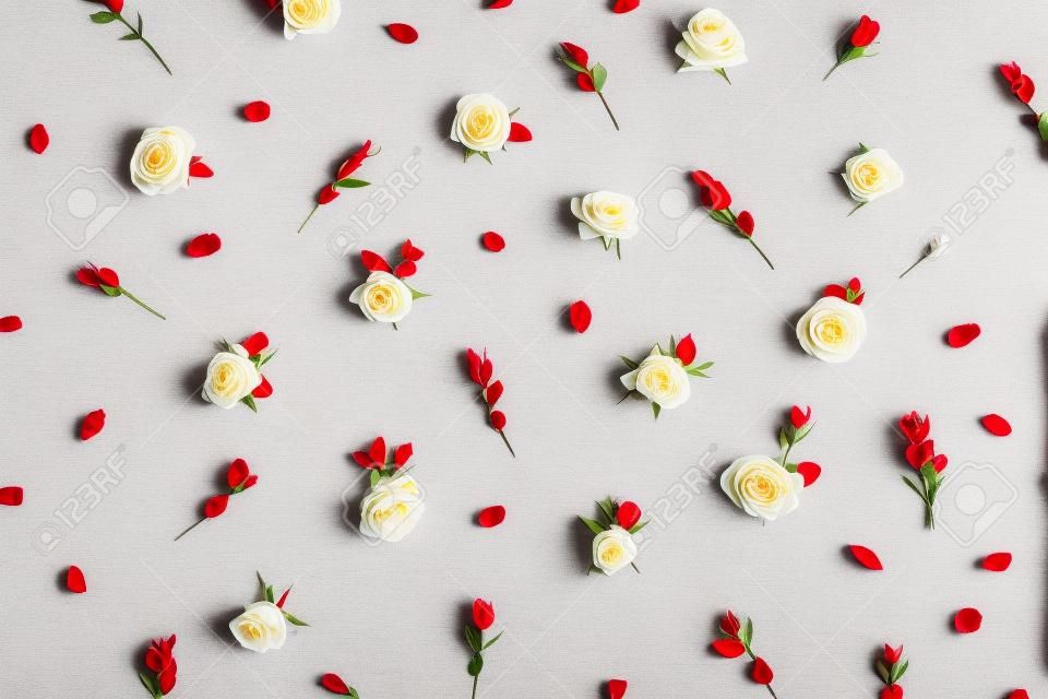 Motivo floreale fatto di boccioli di fiori di rosa rossa e bianca e rami di eucalipto su sfondo bianco. Fat lay, composizione di fiori vista dall'alto.