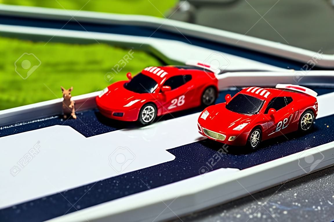 Spielzeug Sportwagen auf einem Steckbrett. Zwei Rot-Rennwagen auf der Rennstrecke
