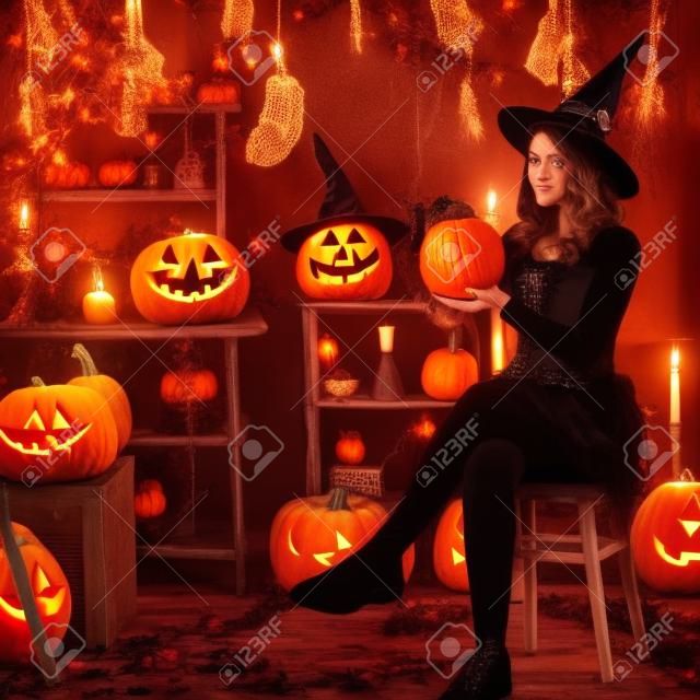 teenage girl dressed as a witch with pumpkins on the background of decor for Halloween