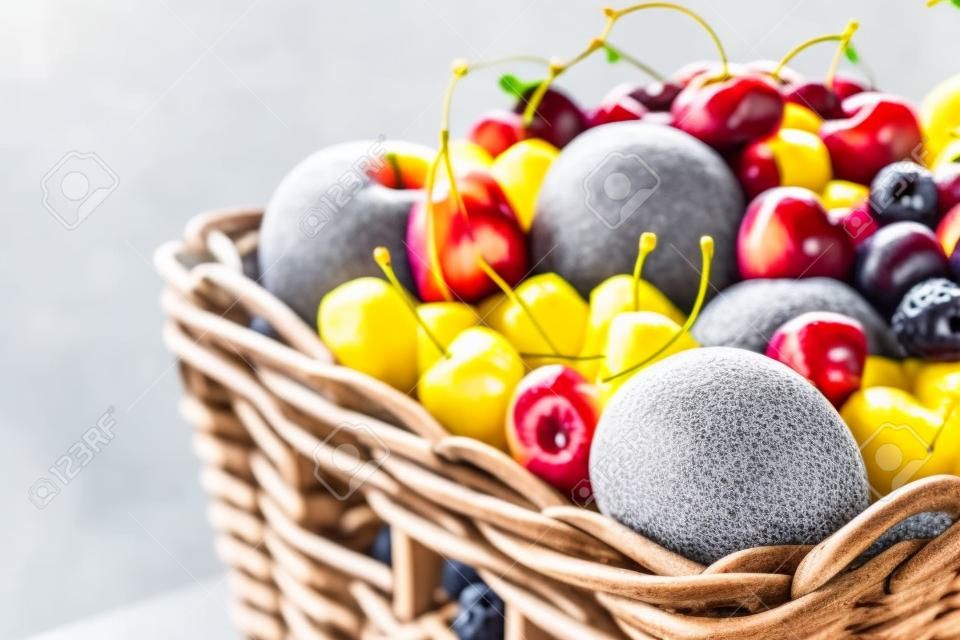 Panier plein de fruits et de baies d'été juteux : cerise, pomme, nectarine, mangue, citron. Fond texturé gris avec espace de copie. Concept d'alimentation saine.