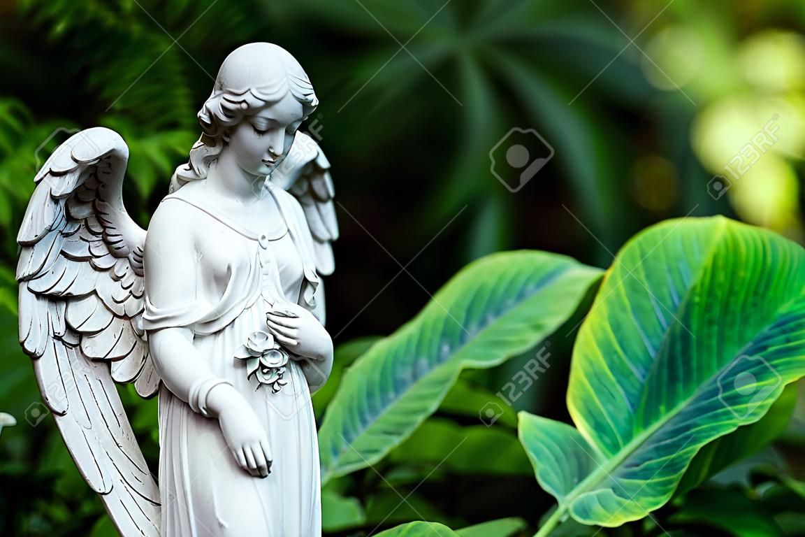 Statue en marbre d'ange avec les yeux fermés au fond vert jardin d'été.