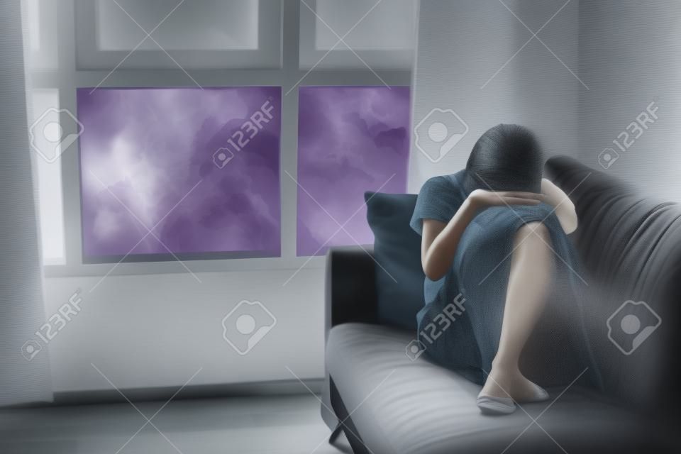 Концепция депрессии и тревоги женщины в позе плода на диване с мрачными цветами. Скопируйте пространство.