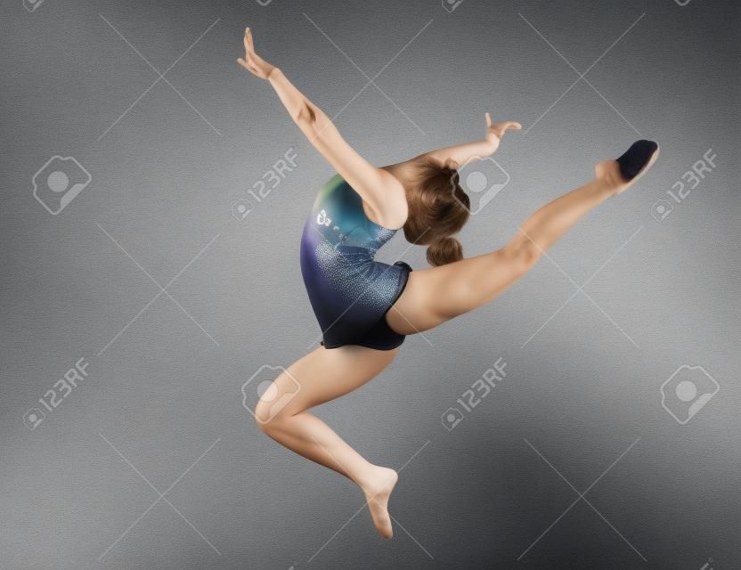 tiener doen gymnastiek dans in springen op een grijze achtergrond