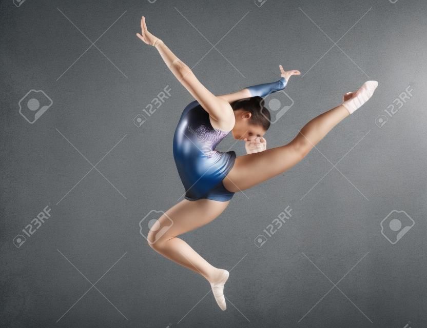 青少年做体操舞蹈在灰色的背景上跳跃