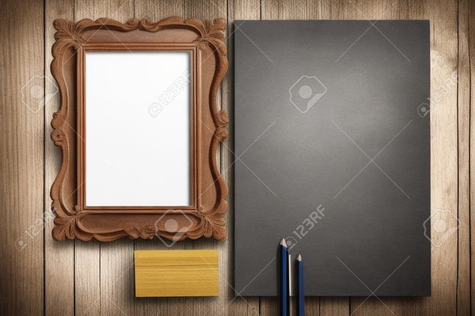 The mockup on wooden background with vintage old picture frame, pen, pencil, white blank paper for writing