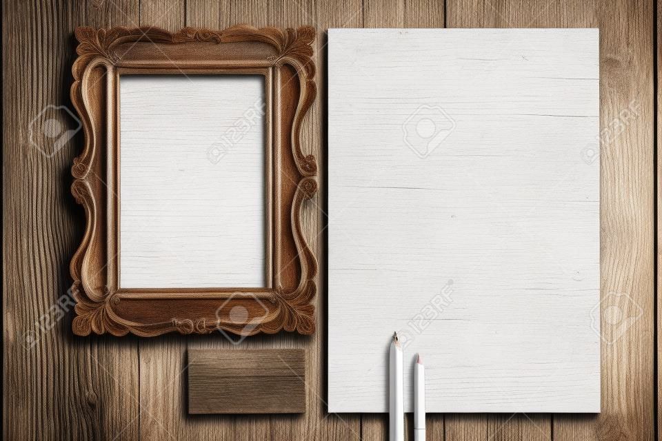 The mockup on wooden background with vintage old picture frame, pen, pencil, white blank paper for writing