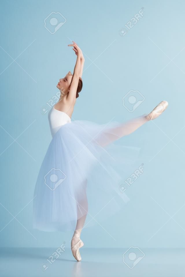 Portrait of the classical ballerina  in white dress on blue background