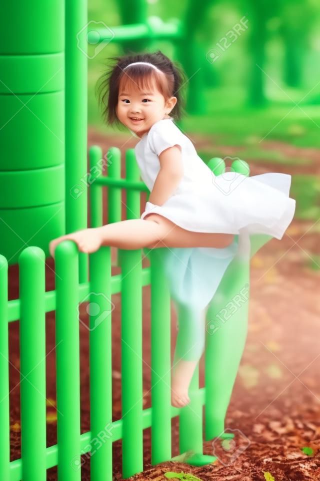 The little girl at playground against park or green forest