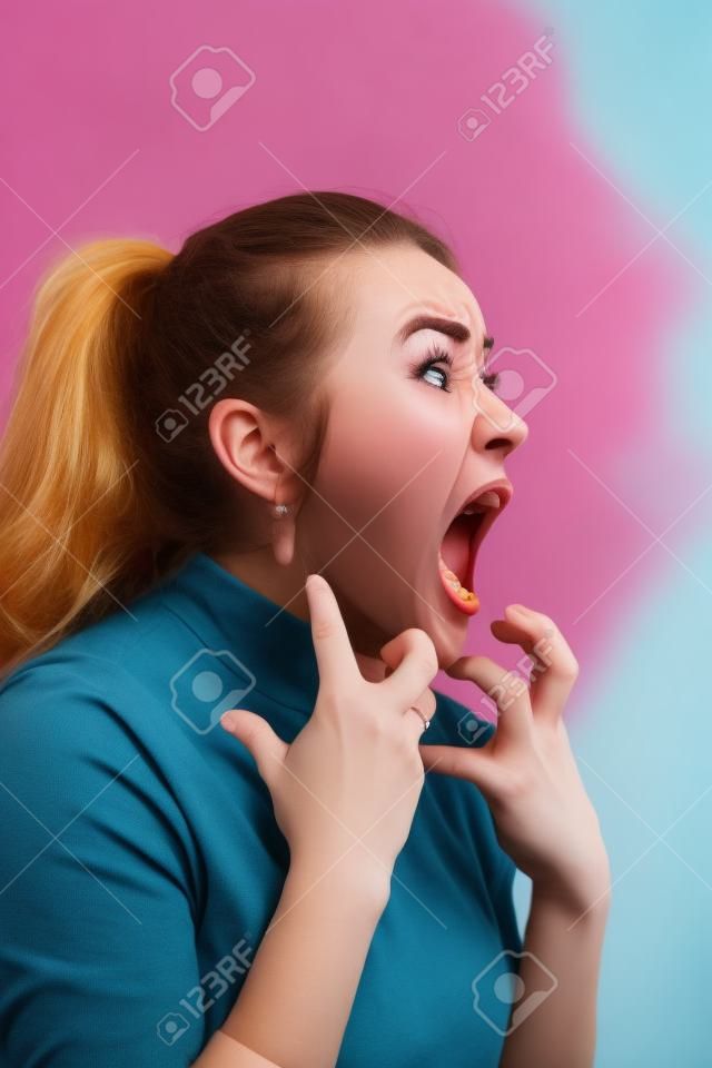 The young emotional angry woman screaming on pastel studio background