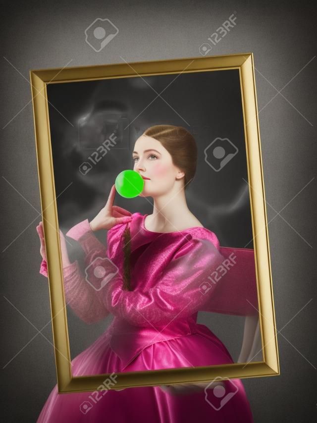 Ritratto di una ragazza che indossa un abito da principessa o contessa su uno studio scuro. ritratto attraverso la cornice con gomma da masticare