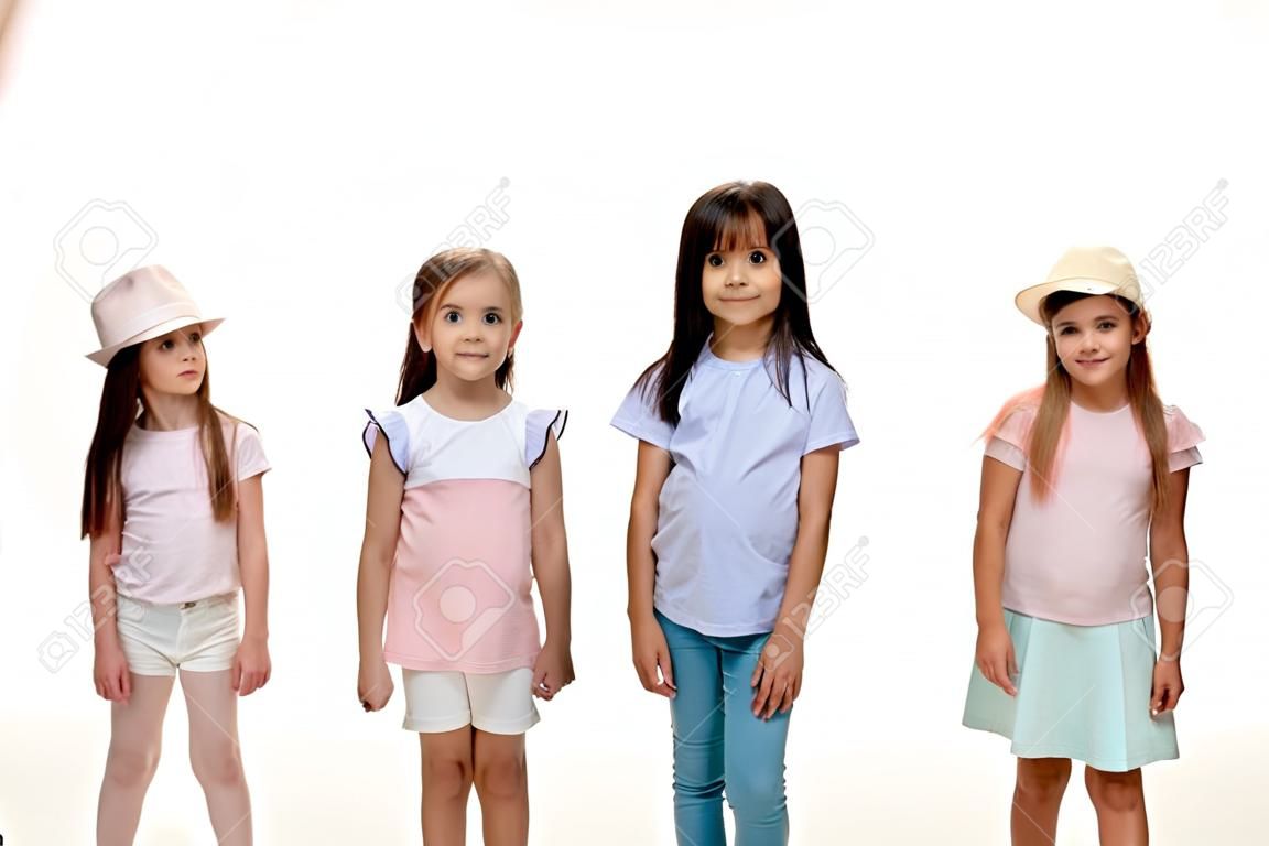 Das Porträt von glücklichen, süßen kleinen Kindern, Jungen und Mädchen in stilvoller Freizeitkleidung, die die Kamera gegen die weiße Studiowand betrachten. Konzept für Kindermode und menschliche Emotionen