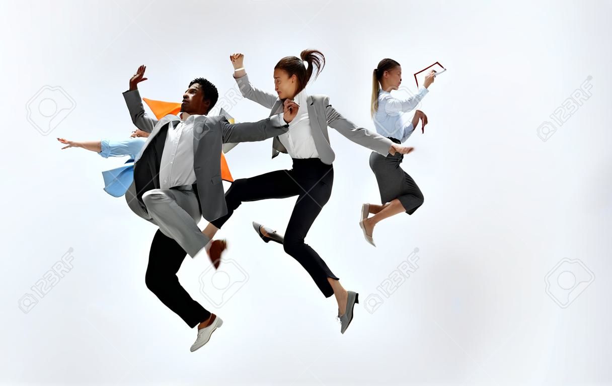 Gelukkige zakenvrouw en Afrikaanse man dansen in beweging geïsoleerd op witte studio achtergrond. Flexibiliteit en gratie in het bedrijfsleven. Menselijke emoties concept. Kantoor, succes, professioneel, geluk, expressie concepten