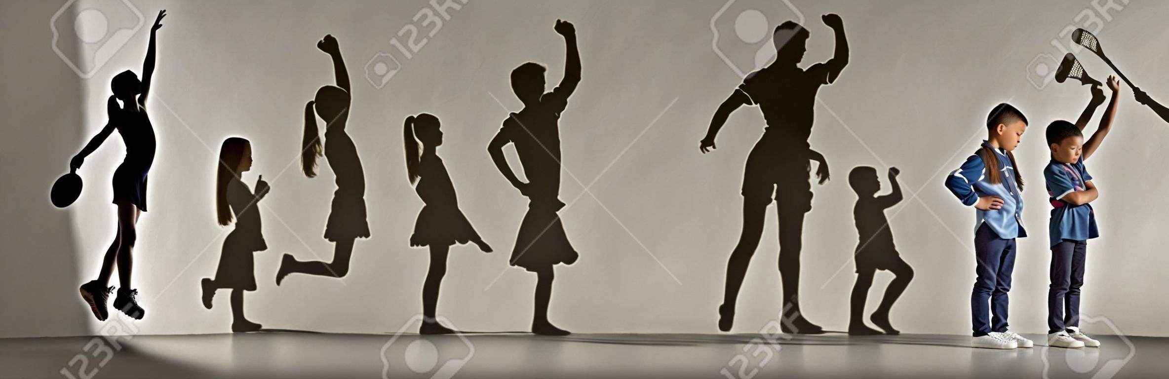 Kindheit und Traum von einer großen und berühmten Zukunft. Konzeptionelles Bild mit Jungen und Mädchen und Schatten von fitten Athleten, Hockeyspielern, Bodybuildern, Ballerinas. Kreative Collage aus 2 Modellen.