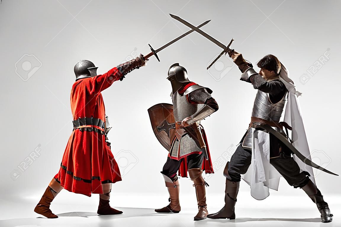 Brave armored knights with professional weapon fighting isolated on white studio background. Historical reconstruction of native fight of warriors. Concept of history, hobby, antique military art.