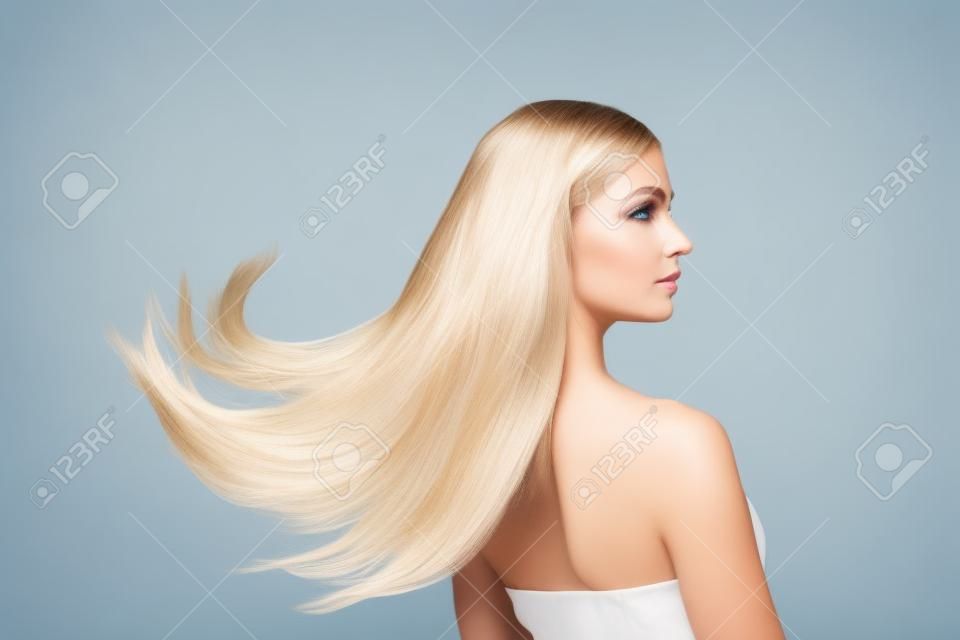 Welle. Schönes Modell mit langen glatten, fliegenden blonden Haaren auf weißem Studiohintergrund. Junges kaukasisches Modell mit gepflegter Haut und Haaren, die in der Luft wehen. Konzept der Salonpflege, Schönheit, Mode.