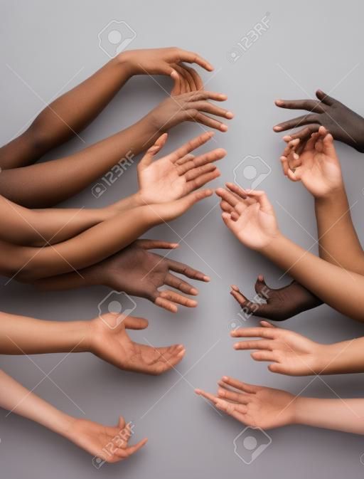 Ludzkość. ręce różnych ludzi w kontakcie na białym tle na szarym tle studio. pojęcie relacji, różnorodności, integracji, wspólnoty, wspólnoty. nieważkie dotykanie, tworząc jedną całość.