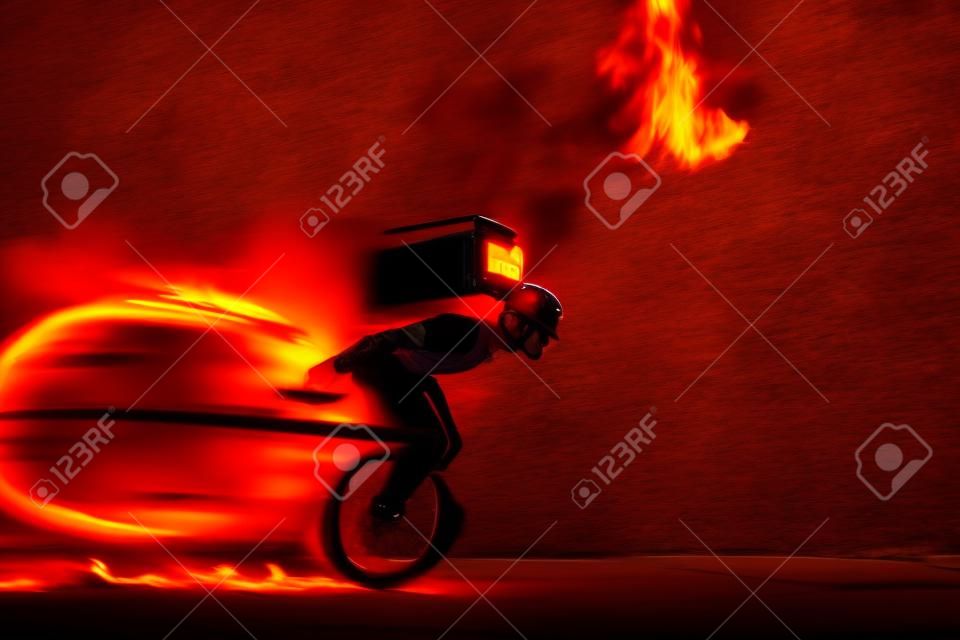 One the go. Fast delivery service - deliveryman on unicycle driving with order in fire on dark background. Copyspace for ad. Super fast shipping of food and goods orders during quarantine.