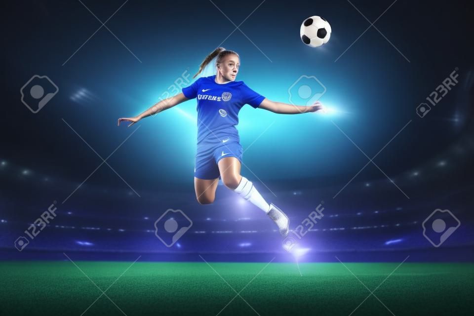 Jonge vrouwelijke voetballer of voetballer in blauwe sportkleding en laarzen schoppen bal in de sprong bij het stadion in zaklampen, spotlights. Concept van professionele sport, hobby, beweging, beweging. 3D render.