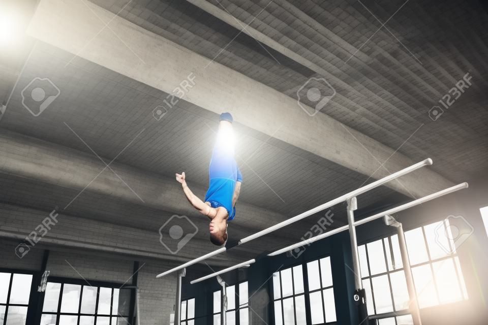 Skillful. Little male gymnast training in gym, composed and active. Caucasian fit boy, athlete in sportswear practicing in exercises for strength, balance. Movement, action, motion, dynamic concept