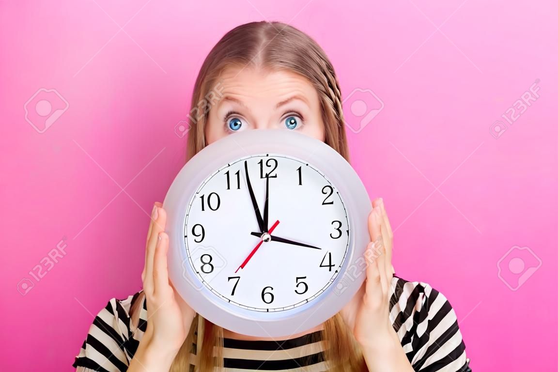 Young woman holding a clock showing nearly 12