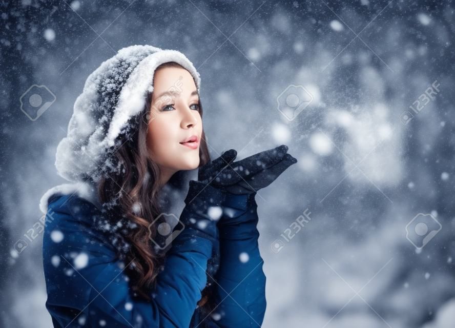 Glückliche junge Frau mit Winterkleidung Schnee weht