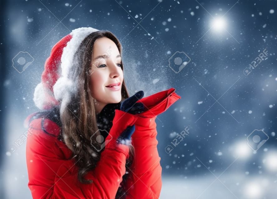 Glückliche junge Frau mit Winterkleidung Schnee weht