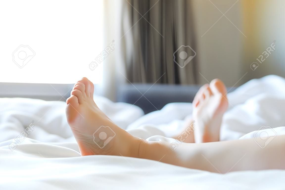 Feet of unidentifiable person sticking out from blanket in morning wake up scene