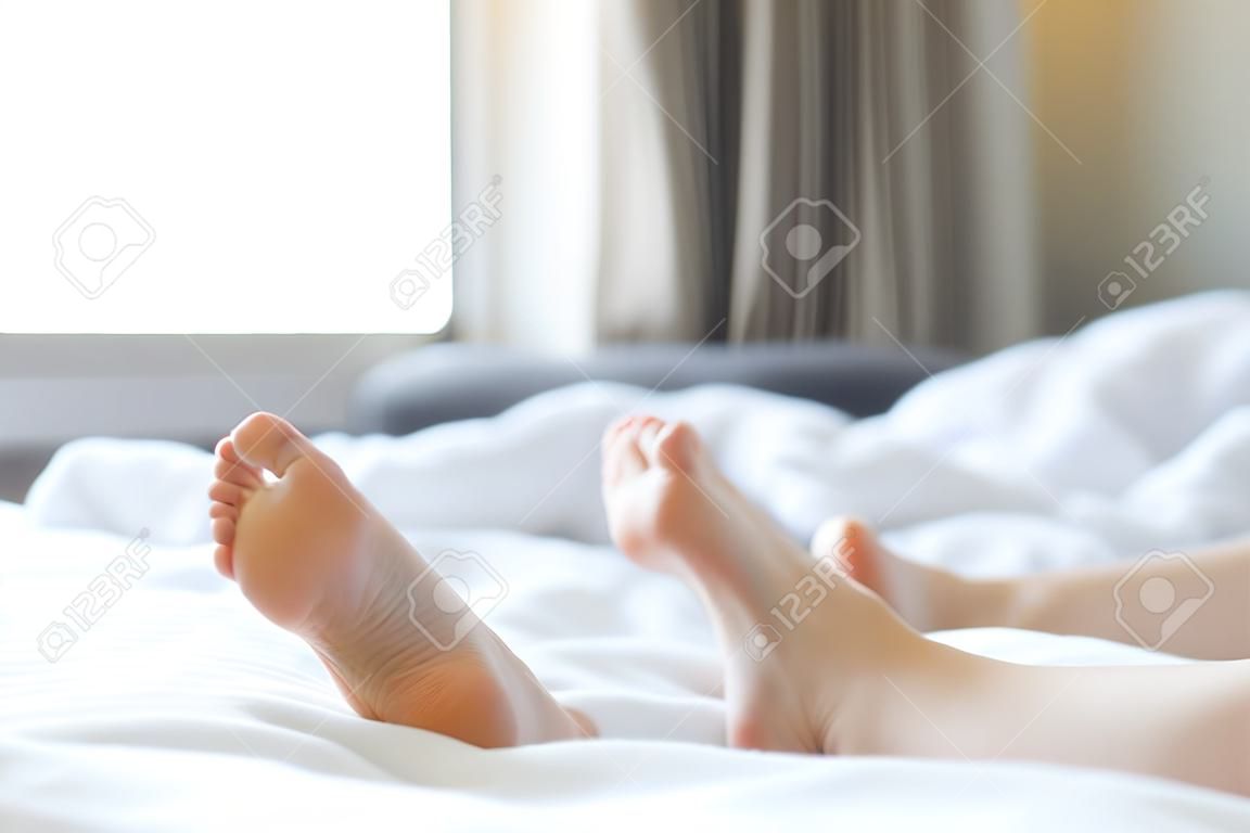Feet of unidentifiable person sticking out from blanket in morning wake up scene