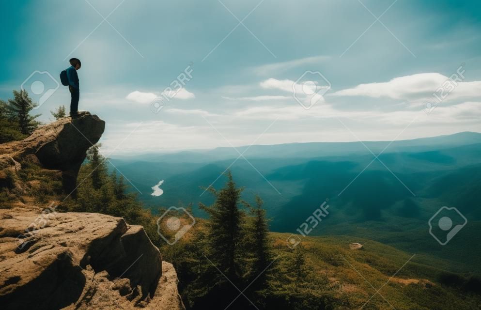 Человек на краю скалы с видом на горы внизу
