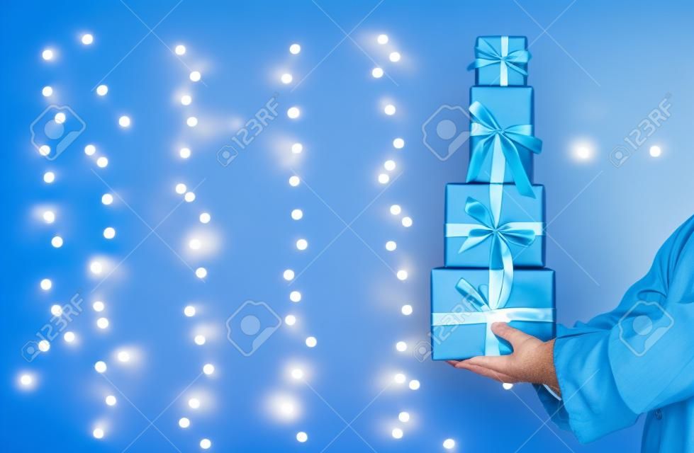 聖誕老人舉行聖誕禮品盒閃亮的淺藍色背景上