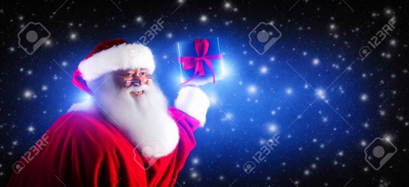 Santa holding a Christmas gift on a shiny light background