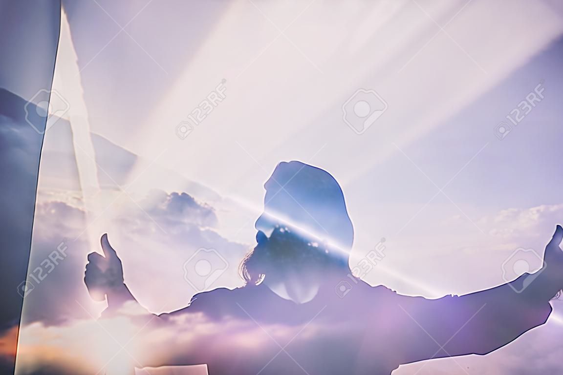 Abstract Dubbele blootstelling van Jezus Silhouette met Lichte Stralen en Wolken.