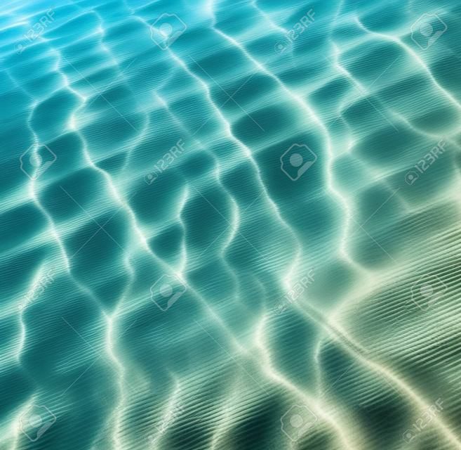 透明的水波紋，浪沙和陽光照射。海底背景