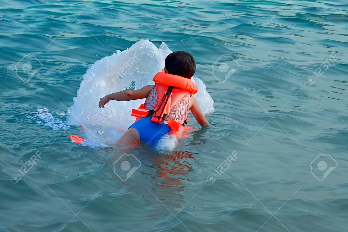 swimming boy with life jacket and pattern of water of sea