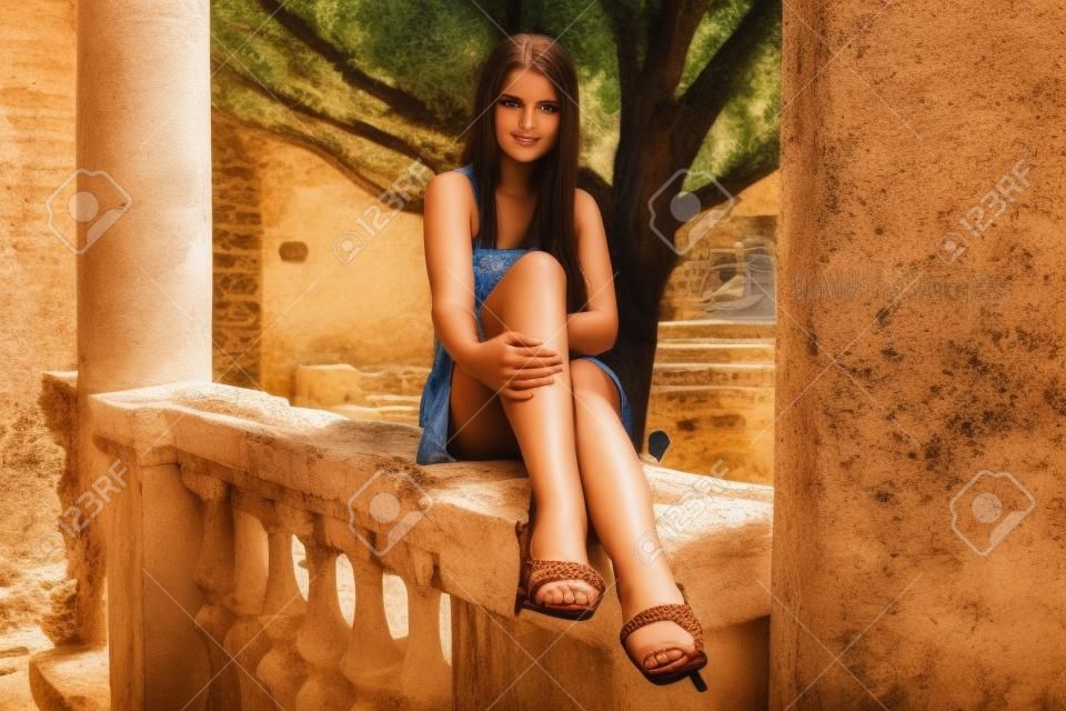 Beautiful brunette girl near greece-style ancient building in summer