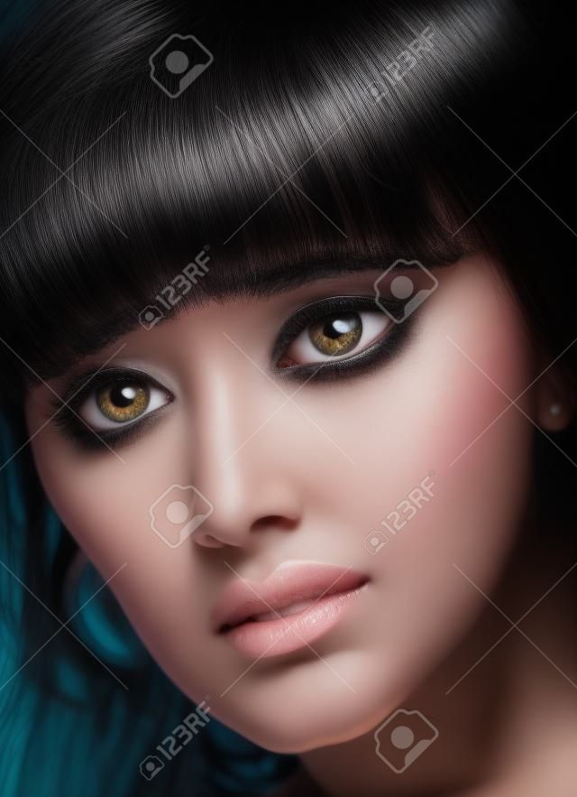 Closeup of the face of black haired women with big eyes.