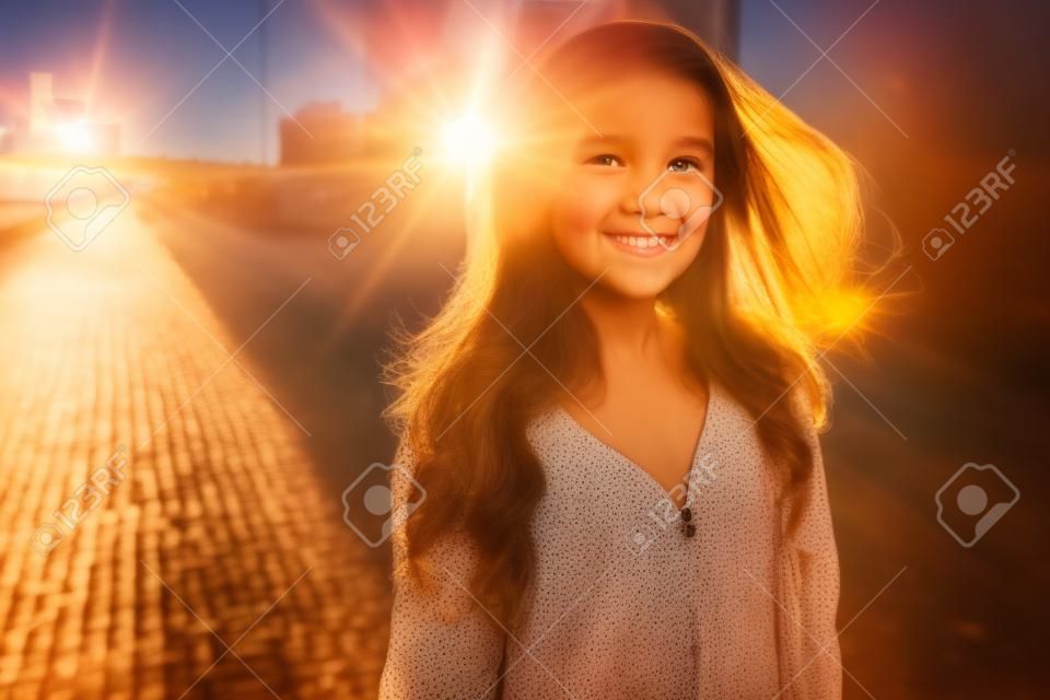Happy girl posing in city backlit by sunset sun