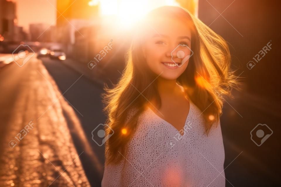 Happy girl posing in city backlit by sunset sun
