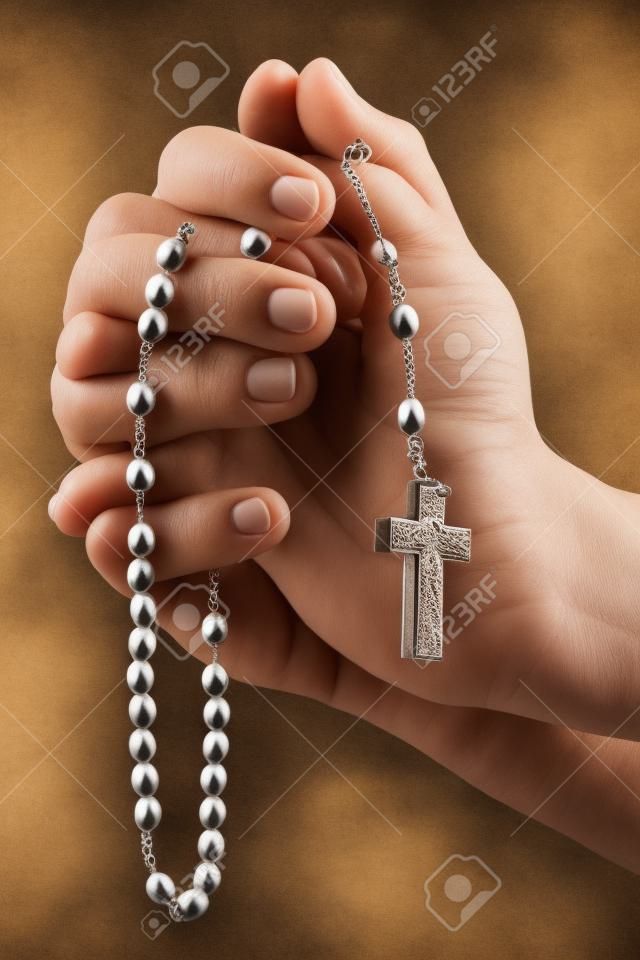 Christian humana rezando con el rosario en las manos