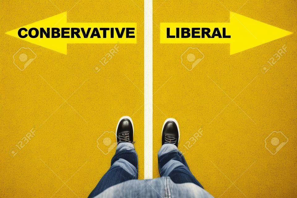 Conservative vs Liberal text on yellow arrows on asphalt ground, feet and shoes on floor, personal perspective footsie concept