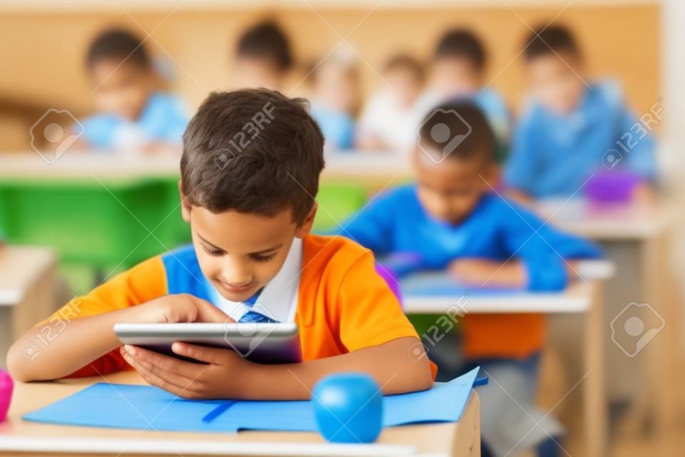 carino scolaro elementare utilizzando un computer tablet in aula