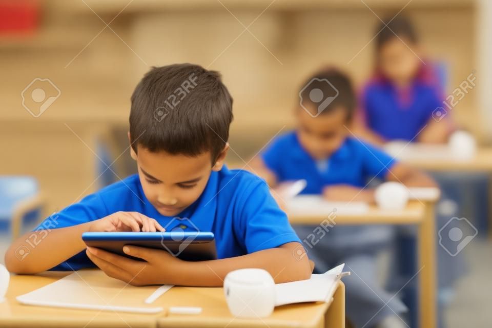 carino scolaro elementare utilizzando un computer tablet in aula