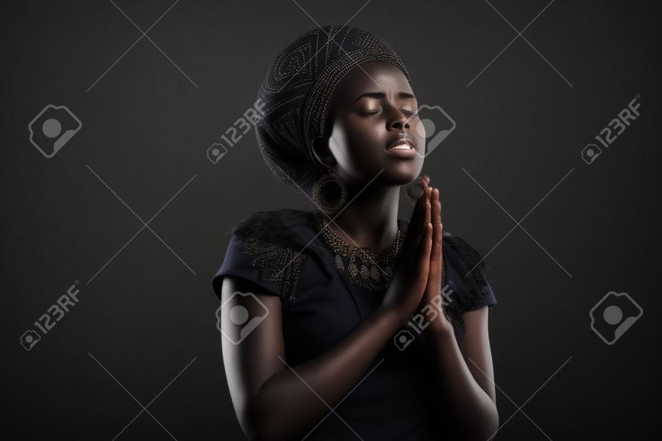 religiosa giovane donna africana pregando su sfondo nero