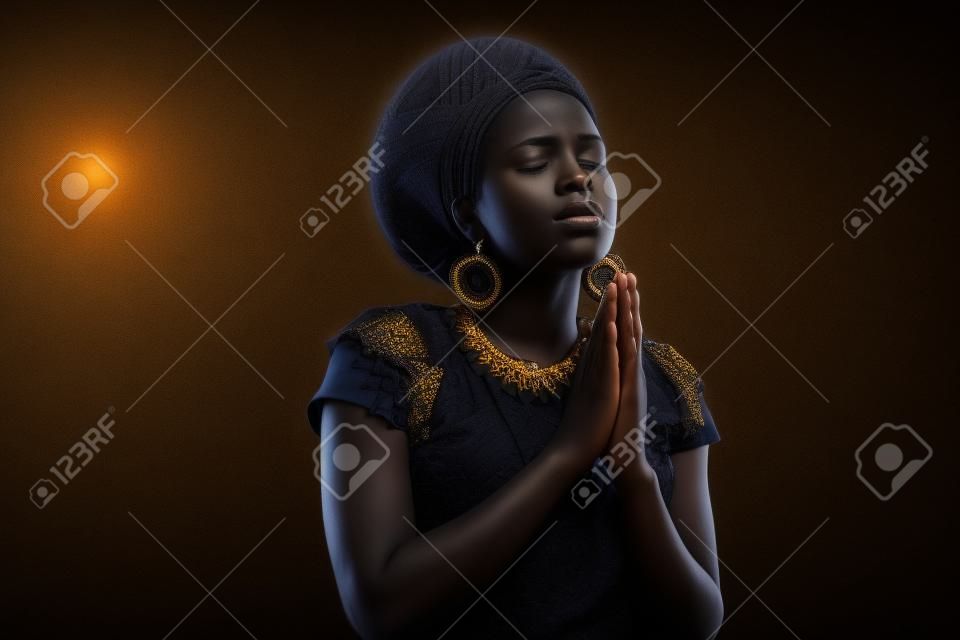 religious young african woman praying over black background